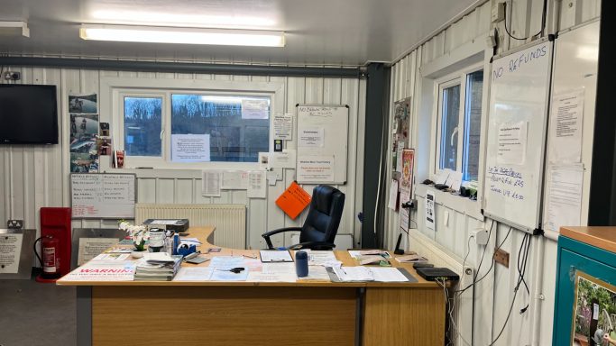 A tidy office with a desk, chair, whiteboards, and large window.